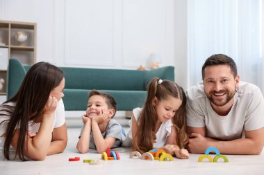 Aileler ve çocukları evde sıcak zeminde oyuncaklarla oynuyorlar. Isıtma sistemi