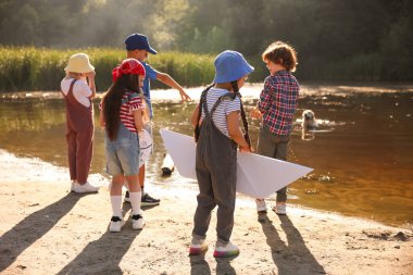 Çocuklar doğada gölün kenarında vakit geçiriyorlar.