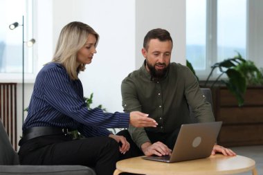 Ofiste dizüstü bilgisayarla çalışan gülümseyen iş ortakları