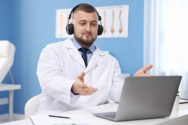 Kulaklıklı doktor içeride bilgisayarla online danışmanlık yapıyor.