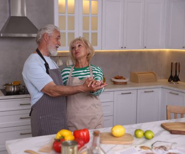 Mutfakta birlikte yemek pişirirken dans eden yaşlı çift.