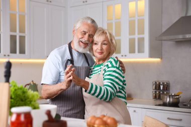 Mutfakta birlikte yemek pişirirken dans eden yaşlı çift.