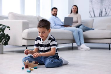 Çocuk sıcak zeminde ailesinin yanında oyuncaklarla oynuyor, seçici bir odak noktası var. Isıtma sistemi