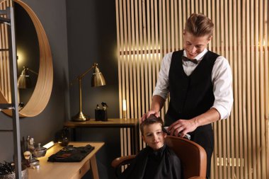 Berber dükkanında küçük bir çocukla çalışan profesyonel berber.