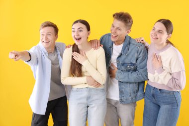 Arkadaşlar gülüyor ve sarı arka planda bir şeye bakıyor. Pozitif duygu