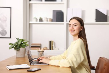 İçerideki ahşap masada dizüstü bilgisayar kullanan metin yazarı