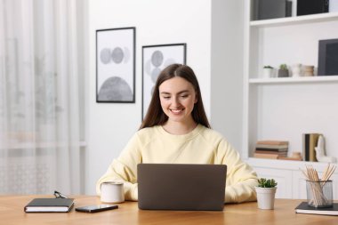 İçerideki ahşap masada dizüstü bilgisayar kullanan metin yazarı