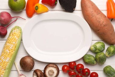 Sağlıklı vejetaryen yemekleri. Beyaz ahşap masa üzerinde farklı ürünlerle çevrili boş bir tabak.