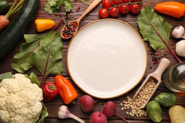 Sağlıklı vejetaryen yemekleri. Tahta masanın üzerinde farklı ürünlerle çevrili boş bir tabak.