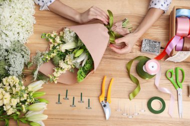 Çiçek buketi yapan bir çiçekçi, ahşap masa, üst manzara