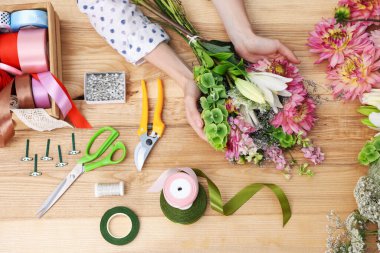 Çiçek buketi yapan bir çiçekçi, ahşap masa, üst manzara