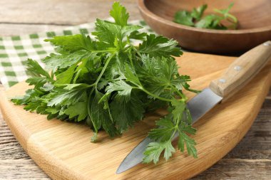 Bir demet taze maydanoz ve bıçak ahşap masada, yakın plan.