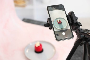 Stüdyoda akıllı telefonla lezzetli bir tatlı çekmek, seçici bir odak noktası. Profesyonel yemek fotoğrafçılığı.