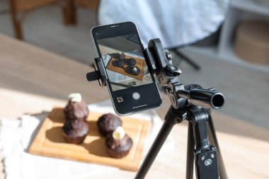Stüdyoda akıllı telefonla çikolatalı kek çekmek, yakın çekim. Profesyonel yemek fotoğrafçılığı.