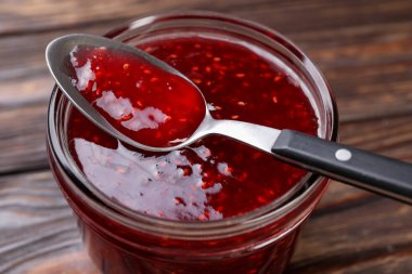 Cam kavanozda tatlı ahududu reçeli ve masada kaşık, yakın plan.