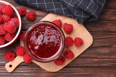 Cam kavanozda tatlı ahududu reçeli ve tahta masada böğürtlen.