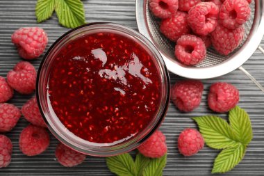 Cam kavanozda tatlı ahududu reçeli ve koyu gri ahşap masada böğürtlen.