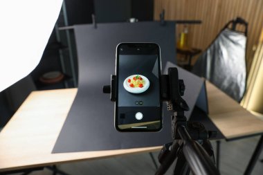 Stüdyoda akıllı telefonla lezzetli makarna çekmek, ekrana odaklanmak. Profesyonel yemek fotoğrafçılığı.