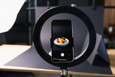 Stüdyoda akıllı telefonla lezzetli makarna çekmek, ekrana odaklanmak. Profesyonel yemek fotoğrafçılığı.