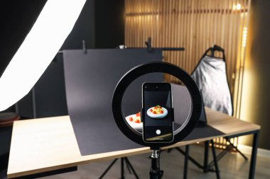 Stüdyoda akıllı telefonla lezzetli makarna çekmek, ekrana odaklanmak. Profesyonel yemek fotoğrafçılığı.