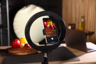 Stüdyoda akıllı telefonla sebze çekmek, ekrana odaklanmak. Profesyonel yemek fotoğrafçılığı.