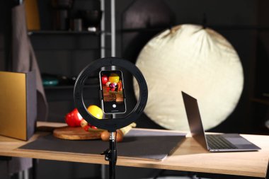 Stüdyoda akıllı telefonla sebze çekmek, ekrana odaklanmak. Profesyonel yemek fotoğrafçılığı.