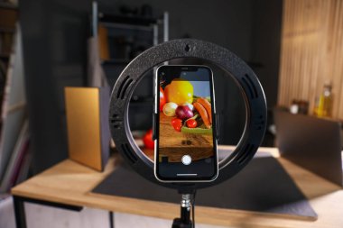 Stüdyoda akıllı telefonla sebze çekmek, ekrana odaklanmak. Profesyonel yemek fotoğrafçılığı.