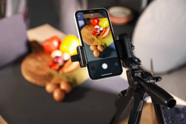 Stüdyoda akıllı telefonla sebze vurmak, seçici bir odak noktası. Profesyonel yemek fotoğrafçılığı.