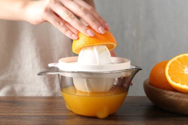 Meyve suyu. Tahta masada portakallı kadın meyve sıkacağı kullanıyor, yakın plan.