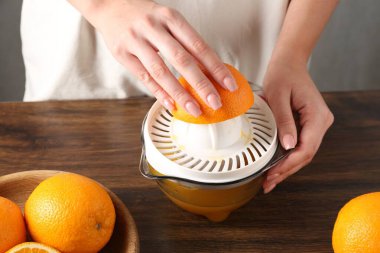 Meyve suyu. Tahta masada portakallı kadın meyve sıkacağı kullanıyor, yakın plan.