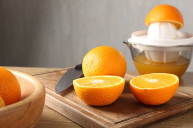 Meyve suyu. Taze portakallar, meyve sıkacağı ve bıçak ahşap masada, yakın plan.