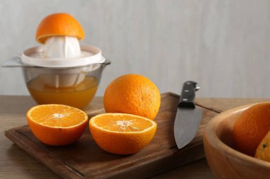 Meyve suyu. Taze portakallar, meyve sıkacağı ve bıçak ahşap masada, yakın plan.