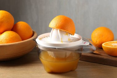 Meyve suyu. Meyve sıkacağı ve taze portakallar ahşap masada, yakın plan.