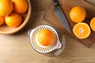 Meyve suyu. Meyve sıkacağı, taze portakal ve bıçak ahşap masada, düz yerde.