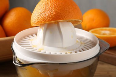 Meyve suyu. Meyve sıkacağı ve taze portakallar masada, yakın plan.