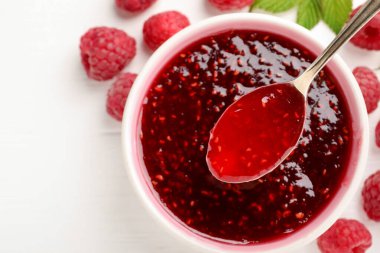 Tatlı ahududu reçeli kasede, böğürtlen ve yeşil yapraklar beyaz masada, düz yerde. Metin için boşluk