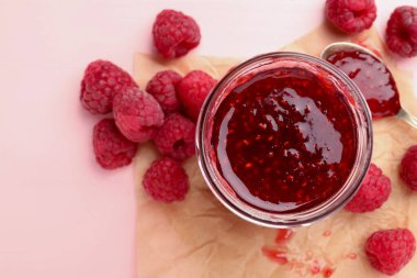 Cam kavanozda tatlı ahududu reçeli ve pembe ahşap masada böğürtlen.