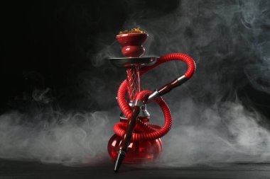 Siyah arka planda duman olan ahşap masada nargile.