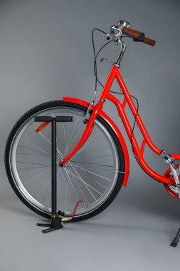 Gri arkaplanda bisiklet ve manuel hava pompası, yakın plan.