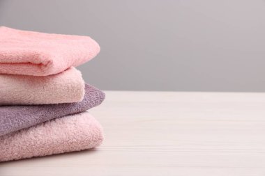 Hafif ahşap masadaki yumuşak havlu yığını gri arka plana karşı, yakın plan. Metin için boşluk