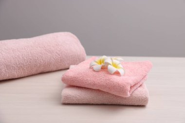 Pembe havlular ve tesisat çiçekleri açık ahşap masa üzerinde Gri arka plan, yakın plan