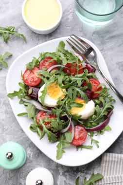 Lezzetli salata roka, sebze ve yumurta gri masada servis edilir.