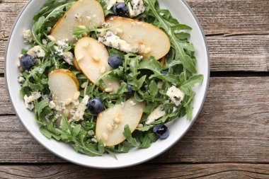 Lezzetli salata roka, armut, mavi peynir, fıstık ve böğürtlenler ahşap masada, üst manzara