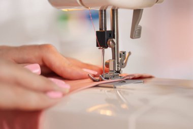 Atölyede dikiş makinesi ve kumaşla çalışan bir kadın.