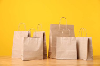 Turuncu arka plana karşı ahşap masada bir sürü kese kağıdı var.