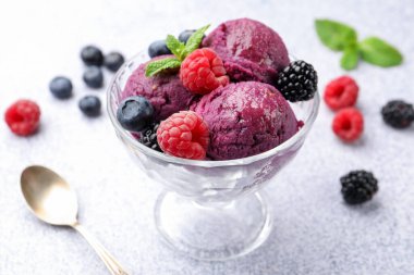 Taze böğürtlenli lezzetli şerbet ve tatlı kasesinde nane şekeri. Gri desenli masa, yakın plan.