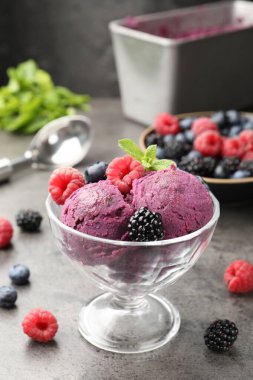 Taze böğürtlenli lezzetli şerbet ve tatlı kasesinde nane. Gri desenli masa, koyu arkaplanlı, yakın plan.