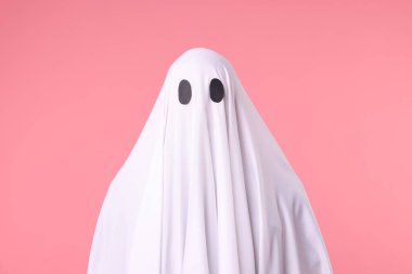 Ürkütücü hayalet. Pembe arka planda beyaz çarşaflı bir adam.