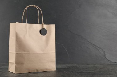 Koyu desenli masa üzerinde boş etiketli kese kağıdı. Gri arka planda, yakın plan. Metin için boşluk