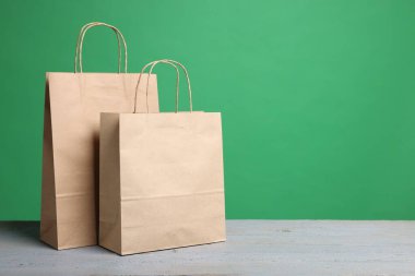 Yeşil arka planda gri ahşap masa üzerindeki Kraft kağıt torbaları. Metin için boşluk